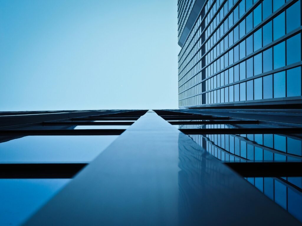 Low angle view of a modern skyscraper with reflective glass facade and blue sky.
